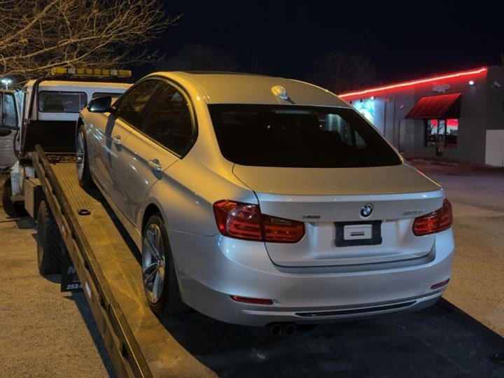 White BMW being loaded onto a rollback at night in Greenville, NC