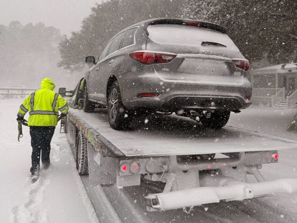 Rollback operator loading an Infiniti QX60 during a snowstorm in Newport, NC